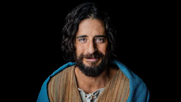 Retrato cercano de Jesús en The Chosen, mirada serena sobre fondo oscuro